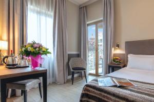 ein Hotelzimmer mit einem Bett, einem Schreibtisch und einem Fenster in der Unterkunft Fragrance Hotel St. Peter in Rom