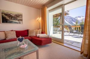 a living room with a red couch and a glass table at Sans Souci EG in Arosa