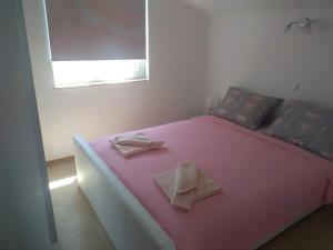 ein rosa Bett mit zwei Servietten darüber in der Unterkunft Edensk vrt classic!!i in Vinkuran