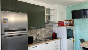 a kitchen with green cabinets and a stainless steel refrigerator at Mazzitelli Apartment in Capo Vaticano