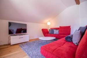een woonkamer met een rode bank en een tv bij Sans Souci OG in Arosa