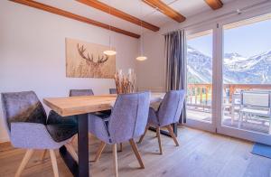een eetkamer met een tafel en stoelen en uitzicht op de bergen bij Sans Souci OG in Arosa