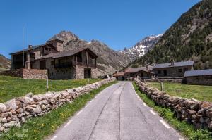 an empty road in a mountain village with a stone wall at Incles Principat in Canillo