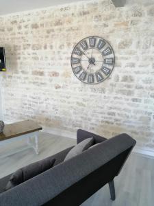 sala de estar con reloj en una pared de ladrillo en Maison de campagne "Beun'aise", en Val-du-Mignon