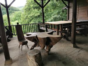 una mesa de madera y un banco en el porche de una cabaña en Hotel Divetsite, en Sliven