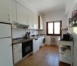 a kitchen with white cabinets and a sink and a dishwasher at Easo Terrace Apartment free private parking and air conditioning in San Sebastián