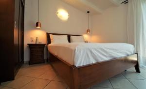 una camera da letto con letto, lenzuola e cuscini bianchi di Hotel Acropol a Párga