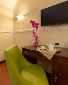 a green chair and a table with a vase of flowers at Hotel Antica Dogana in Turin