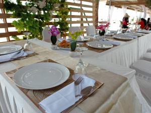 a long table with white plates and silverware on it at Hello Bintan in Kangkakawal