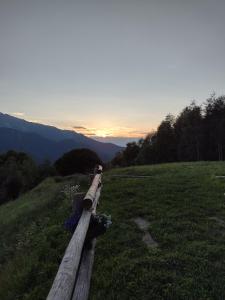 una valla de madera en un campo con la puesta de sol en el fondo en Le Baite di Baudinet - Trek&Relax, en Chiusa di Pesio