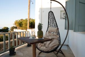 a swing chair on a porch with a table and a pineapple at Iviskos House Apollonia Sifnos in Apollonia