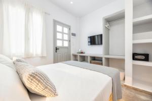 a white bedroom with a bed and a window at Pelican Paros in Parikia