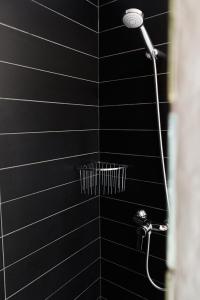 a black tiled shower with a shower head at Apartamento con piscina de temporada a 50m del mar in Port de la Selva