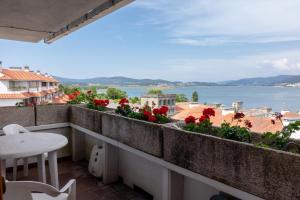 een balkon met rode bloemen en uitzicht op het water bij RIOyMAR Apartamento in A Guarda