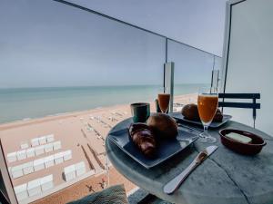 - une table avec une assiette de nourriture et de boissons sur la plage dans l'établissement Genieten van de Vlaamse kust met prachtig zeezicht, au Coq