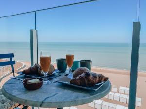德哈恩的住宿－Genieten van de Vlaamse kust met prachtig zeezicht，海滩上的一张桌子,上面放着两杯葡萄酒和面包