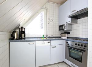 ヘルヌムにあるStrandoase-STW-109の白いキャビネットとシンク付きのキッチン