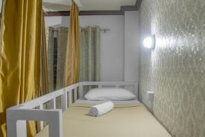 Habitación pequeña con cama y cortina amarilla en Davao Hub Bed and Breakfast en Dávao