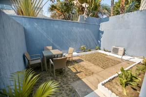 a patio with a table and chairs next to a blue wall at Appartement - Vue sur mer in Pointe-Noire