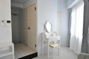 a white bathroom with a mirror and a sink at CRYSTAL ＆ RESORT FUKUOKA in Fukuoka