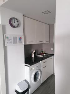 a kitchen with a washing machine and a clock on the wall at Estudio FARO TORROX in Torrox Costa