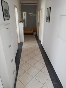 a hallway with white walls and a tiled floor at Apartman G&L in Grebaštica