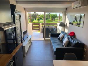 een woonkamer met een zwarte bank en een keuken bij Secret Garden Port Nature Village Naturisme 3 étoiles in Cap d'Agde
