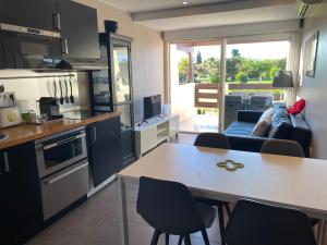 een keuken en een woonkamer met een tafel en stoelen bij Secret Garden Port Nature Village Naturisme 3 étoiles in Cap d'Agde