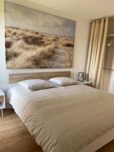 una camera da letto con un letto e un dipinto sul muro di Chez Tibé ad Arcachon