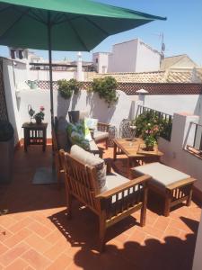 d'une terrasse avec des tables, des chaises et un parasol. dans l'établissement La Llave de la Judería Hotel Boutique, à Cordoue