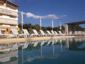 a row of white lounge chairs next to a swimming pool at Alex House in Zakharo