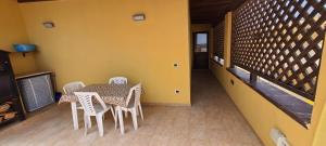 a table and chairs in a room with a yellow wall at Appartamento in Centro in Lampedusa +10 photos