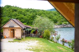 a cabin by the water next to a lake at Apartmani Kod Draskovica in Nikšić