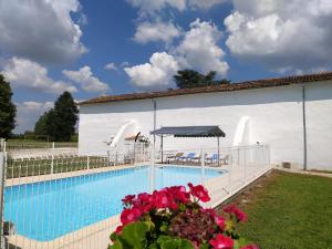 a building with a swimming pool with flowers in front of it at Domaine Moulin D' Elemiah in Gémozac