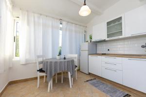 a kitchen with a table and chairs and a kitchen with white cabinets at Apartments Biserka in Božava