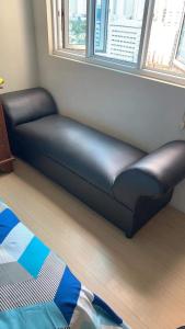 a black couch in a room with a window at Mplace Condo Unit _ Panay Avenue, Quezon City, Philippines in Manila