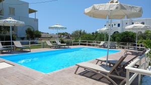 a swimming pool with chairs and umbrellas next to a building at Maria's Rooms & Studios in Agia Anna Naxos
