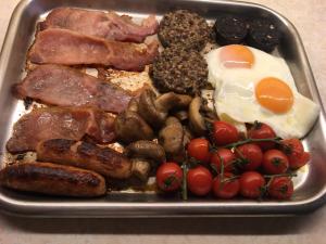 a tray of breakfast food with eggs sausage and tomatoes at Auchenlea bed and breakfast in Coatbridge