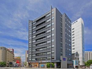 a tall gray building in a city at Comfort Inn Fukuoka Tenjin in Fukuoka