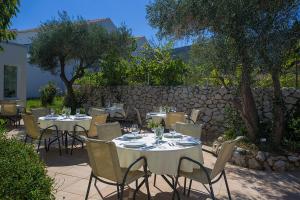 a patio with tables and chairs and a stone wall at Hotel Manora in Nerezine