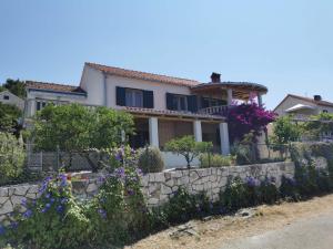 a house with a stone retaining wall and flowers at Apartment Miljenko Tomic 2 in Supetar