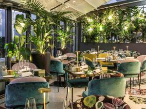 a restaurant with tables and chairs and plants at Sofitel Roma Villa Borghese in Rome