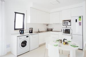 een witte keuken met een wasmachine en een tafel bij Janelas de Salir - By SCH in Salir de Porto