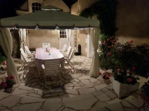 Chenonceau Amboise équitation beauval في Civray-de-Touraine: طاولة وكراسي تحت مظلة على الفناء