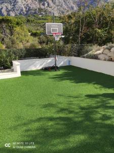 a basketball hoop on a lawn with green grass at Apartments Villa Hadria in Makarska