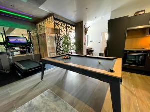 a living room with a pool table and a kitchen at Capsule Wellness - sauna - balneo - machine de sport privatif - PS5 - 2 chambres in Valenciennes