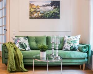 un soggiorno con divano verde e tavolo in vetro di Warsaw Seasons by Alluxe Boutique Apartments a Varsavia