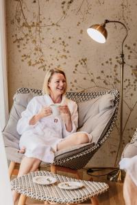 a woman sitting in a wicker chair holding a cup of coffee at Boutique Hotel Hohes Licht in Damuls