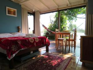 een slaapkamer met een bed en een tafel en stoelen bij Casinha RDS in Guarda do Embaú