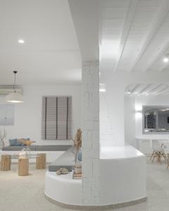 een witte woonkamer met een standbeeld op een tafel bij Mykonos Essence Adults Only in Ornos